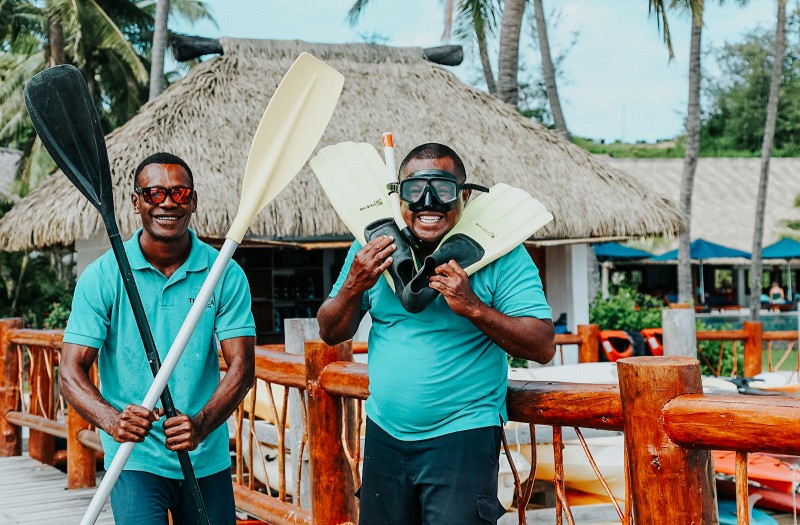 Two Fijian Men holding stand up paddle board oars, flippers & snorkel at Tropica Island Resort. Zero-Carbon Activities